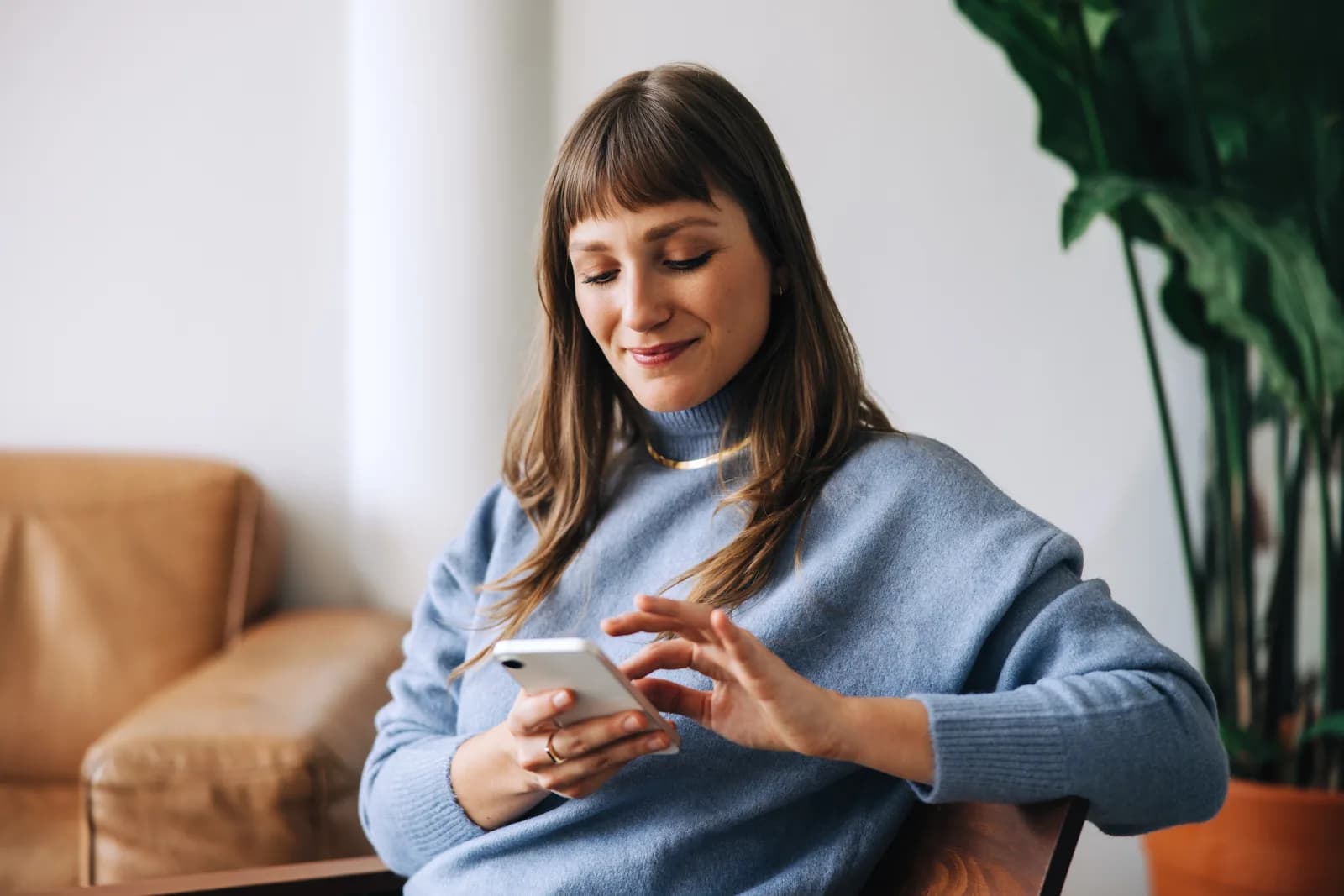 Une femme utilise son téléphone dans sa maison