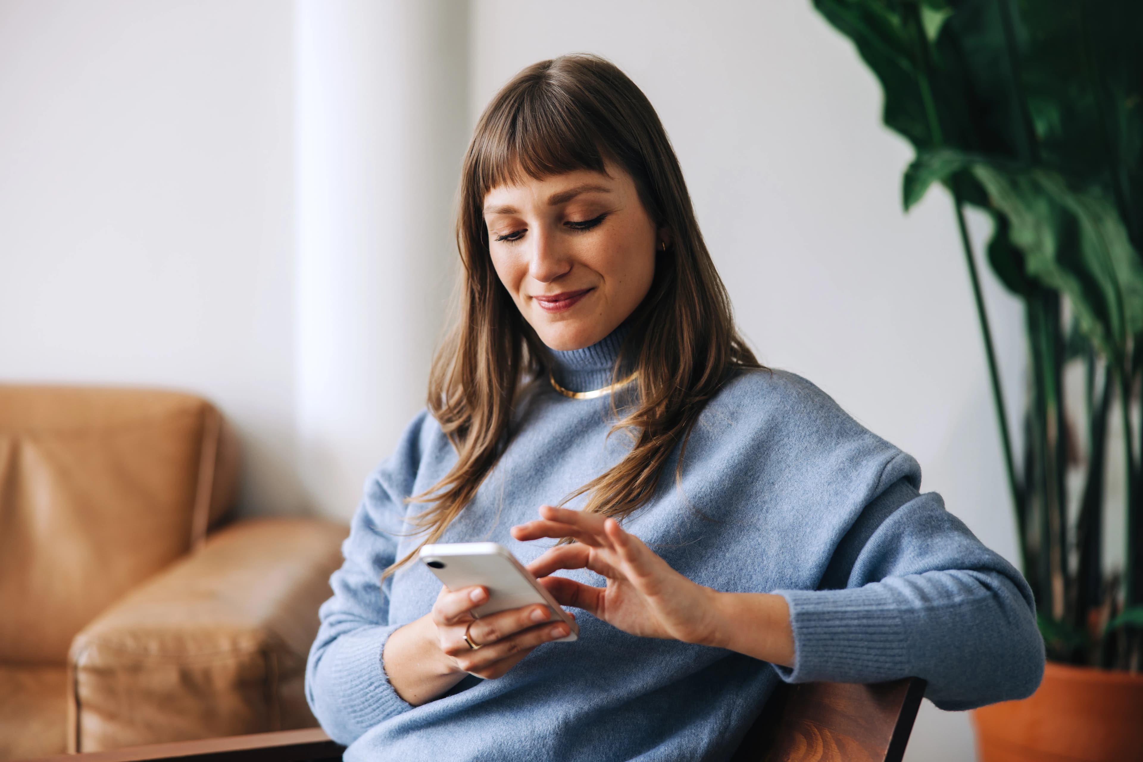 Une femme utilise son téléphone dans sa maison